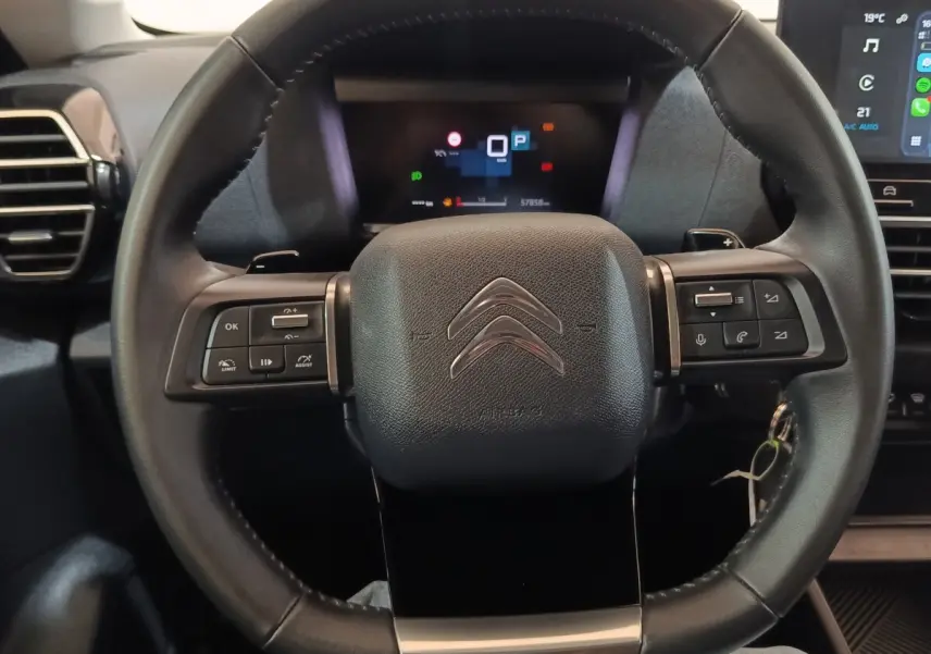 Vue rapprochée du volant cuir noir de la Citroën C4 X 2023 avec commandes multifonctions et tableau de bord digital.