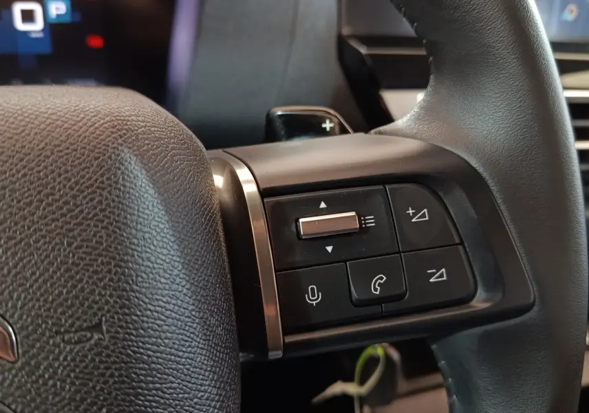 Gros plan sur les commandes au volant cuir noir du Citroën C4 X 2023, avec boutons multifonctions et palettes de changement.