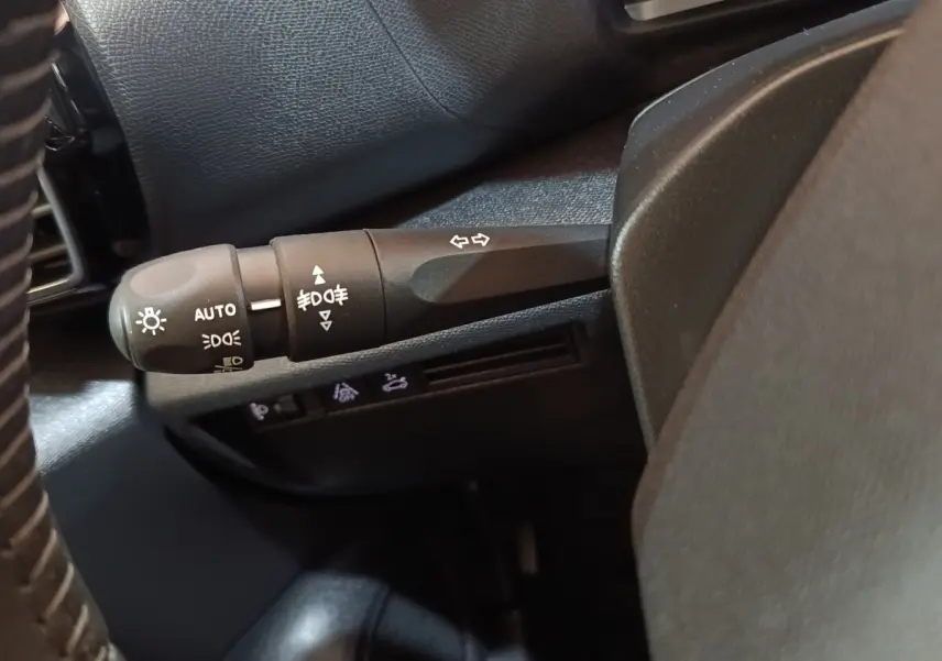 Gros plan sur la commande des feux et clignotants côté gauche du volant dans l’habitacle noir du Citroën C4 X 2023.