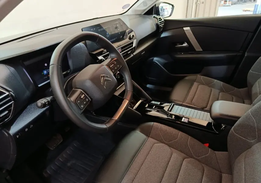 Intérieur de la Citroën C4 X noir, vue côté conducteur, volant cuir multifonctions et écran tactile central.