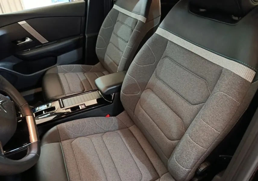 Vue intérieure côté conducteur du Citroën C4 X 2023, sièges tissu gris avec appuie-tête noir et accoudoir central.
