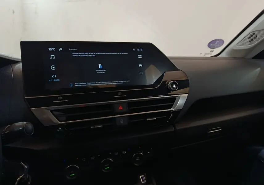 Vue intérieure du tableau de bord de la Citroën C4 X 2023 avec écran tactile central et commandes climatisation.