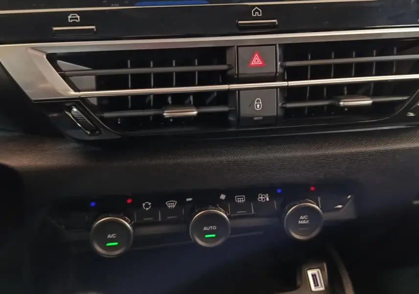 Vue rapprochée du tableau de bord central noir du Citroën C4 X 2023, avec commandes climatisation et prises USB visibles.