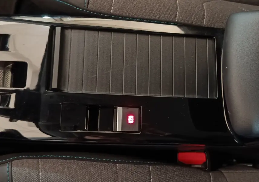 Gros plan sur la console centrale noire avec frein à main électrique allumé et sellerie tissu gris du Citroën C4 X.