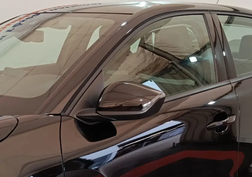 Vue latérale gauche rapprochée d'une Citroën C4 X noire 2023 avec rétroviseur ton caisse et poignée de porte visible.