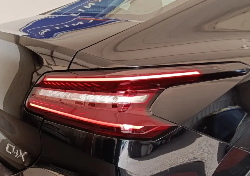 Gros plan sur le feu arrière droit rouge et blanc d'une Citroën C4 X noire, avec logo C4 X visible sur la carrosserie.