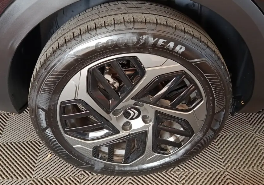 Gros plan sur la roue avant gauche du Citroën C4 X noir, avec jante alliage au design géométrique et pneu Goodyear.