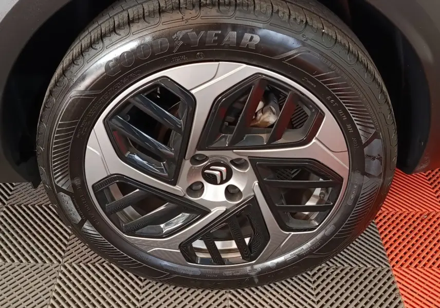 Gros plan sur la roue avant droite d'une Citroën C4 X noire, avec jante alliage au design géométrique bicolore.