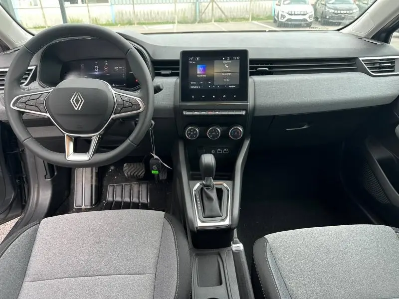Vue intérieure avant de la Renault Clio 2025 gris, tableau de bord avec écran tactile et volant multifonction.