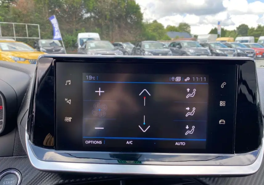 Écran tactile 7 pouces du tableau de bord de la Peugeot 208 noire, avec commandes climatisation visibles.