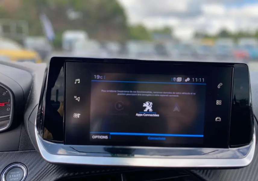 Écran tactile central de la Peugeot 208 2021 en noir, affichant les applications connectées, avec bouton start/stop visible.