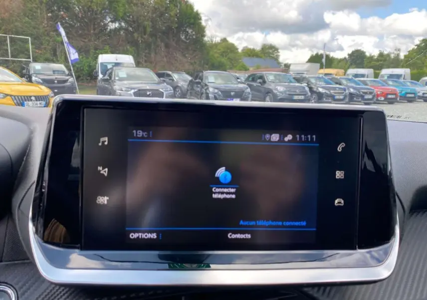 Écran tactile 7 pouces du tableau de bord d'une Peugeot 208 noire, affichant la connexion téléphone.