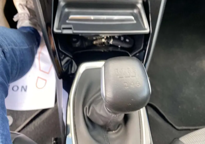 Gros plan sur le levier de vitesses manuel de la Peugeot 208 noire, avec console centrale brillante visible.