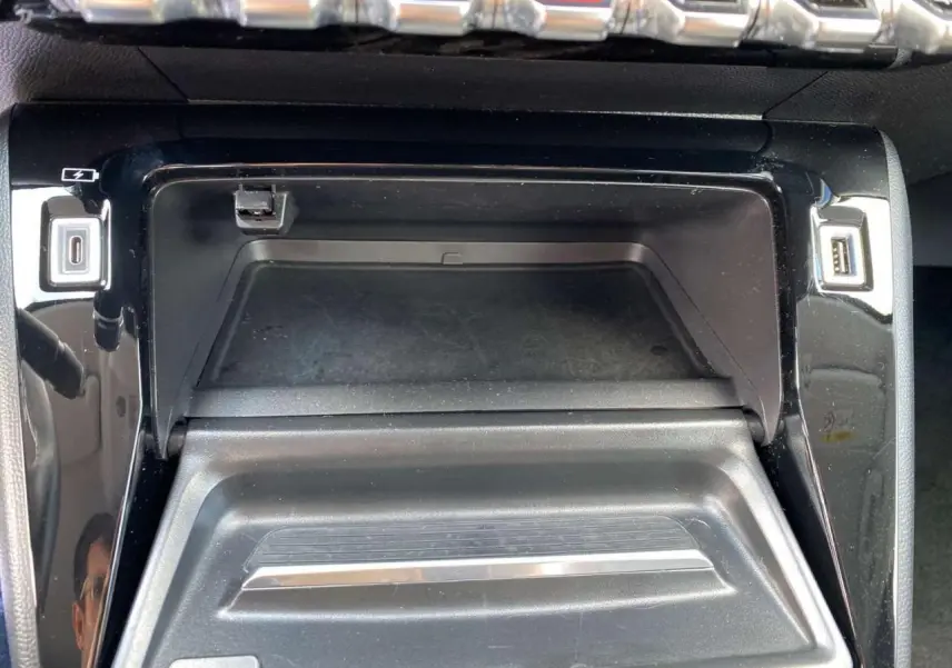 Gros plan sur la console centrale noire de la Peugeot 208 2021 avec ports USB et finition brillante.