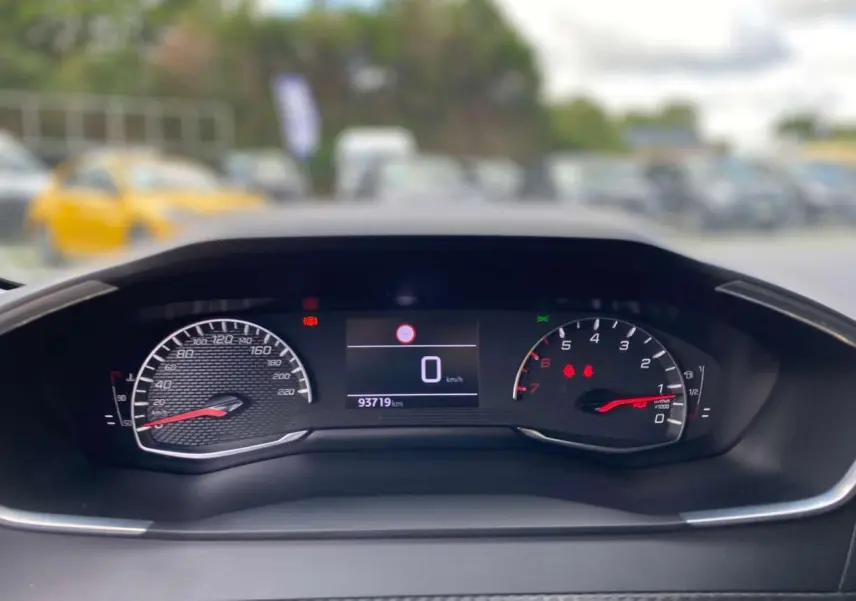 Vue rapprochée du tableau de bord numérique de la Peugeot 208 noire, affichant le compteur et le compte-tours.