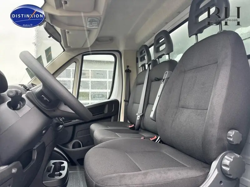 Vue intérieure côté gauche du Fiat Ducato Benne 2023, montrant les sièges noirs et le volant réglable en hauteur.