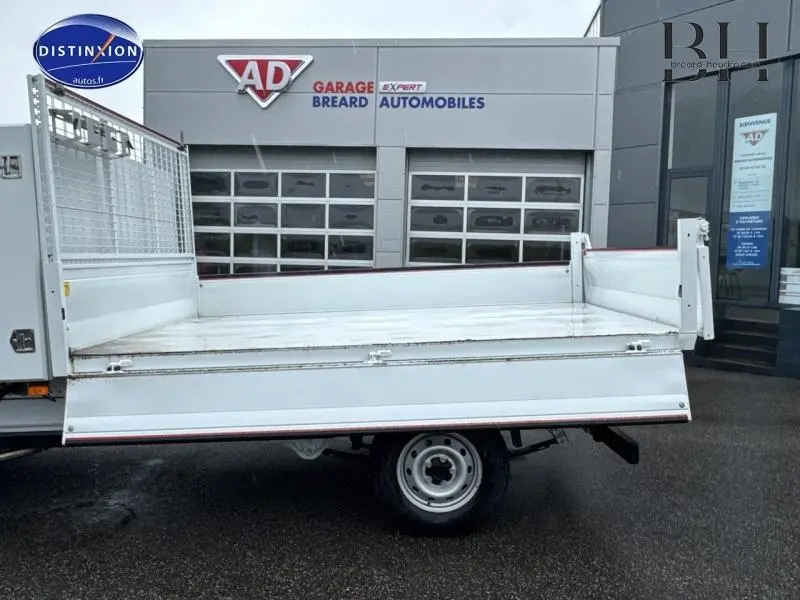 Vue latérale droite d'une benne acier blanche du FIAT Ducato 2023 avec ridelles abaissées sur fond de garage.