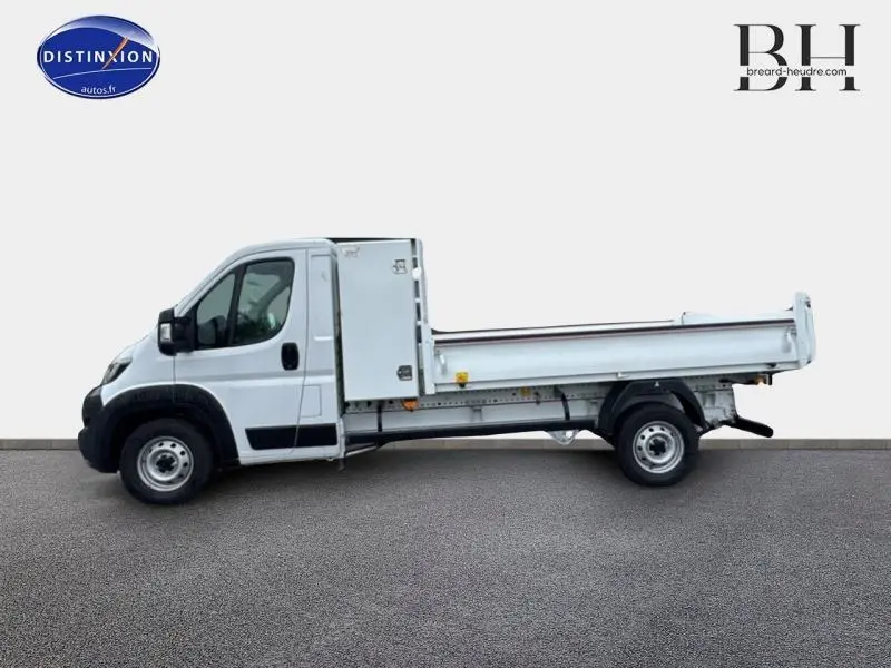 Vue latérale gauche d'un FIAT Ducato Benne blanc 2023 avec benne acier et grand coffre arrière.