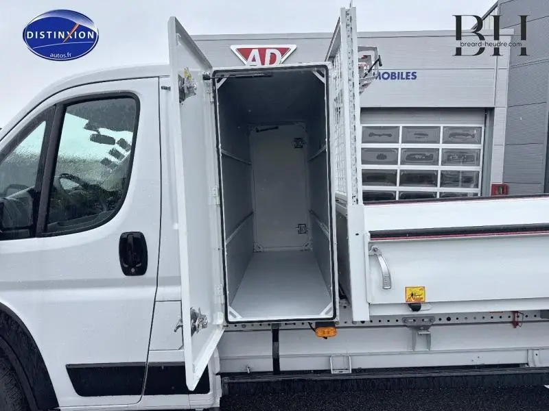 Vue latérale gauche du FIAT Ducato Benne blanc 2023 avec porte de grand coffre acier ouverte sur benne arrière.