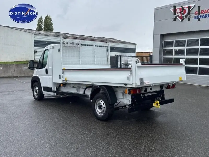Fiat Ducato Benne blanc vu en 3/4 arrière droit, avec benne acier et attelage remorque visible.