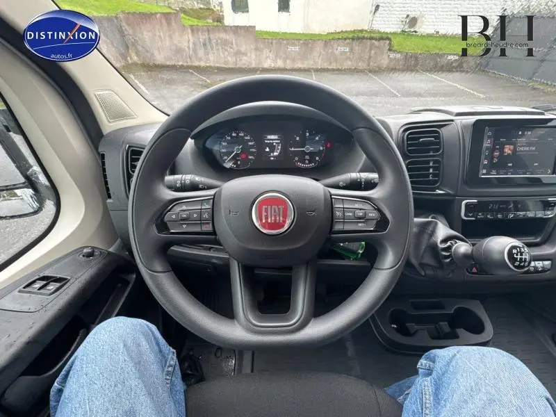 Vue depuis le siège conducteur du volant Fiat et tableau de bord du Ducato Benne 2023 avec levier de vitesses manuel.