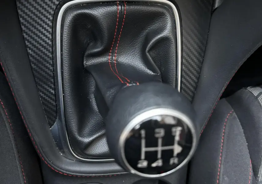 Le levier de vitesses manuel noir avec surpiqûres rouges du MG ZS 1.5L VTI-Tech, vue rapprochée intérieure.