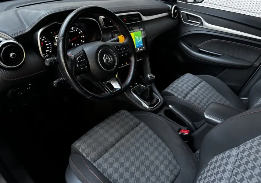 Intérieur avant droit du MG ZS 2022 avec volant cuir, console centrale tactile et sièges gris à motif géométrique.