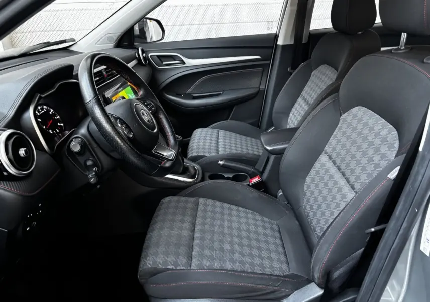 Intérieur avant droit du MG ZS gris clair 2022, sièges tissu à motif pied-de-poule et volant cuir multifonctions.