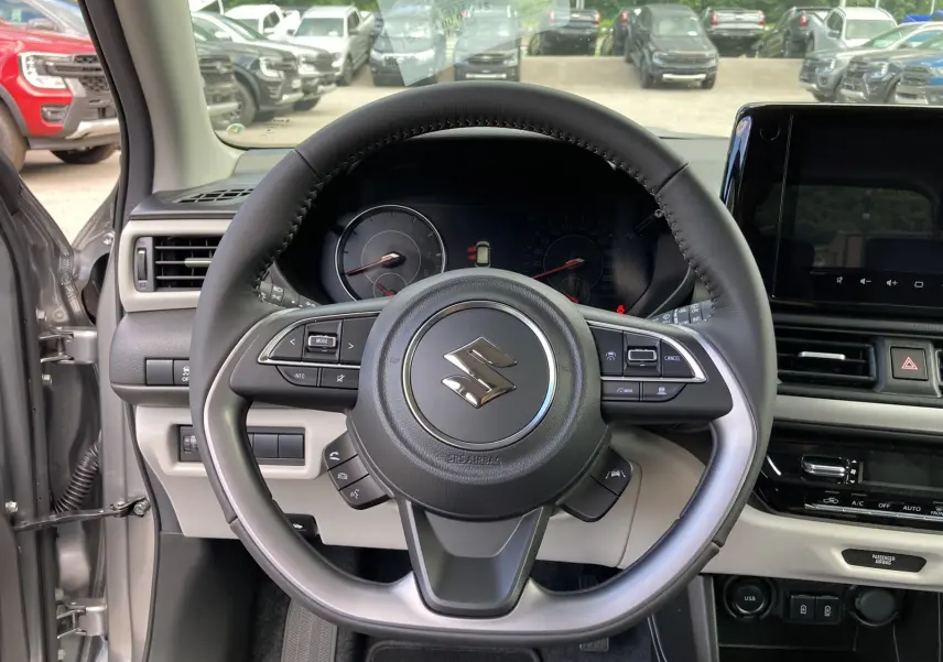 Vue centrée sur le volant cuir multifonctions d'une Suzuki Swift 2025 gris argent premium, tableau de bord et écran tactile visibles