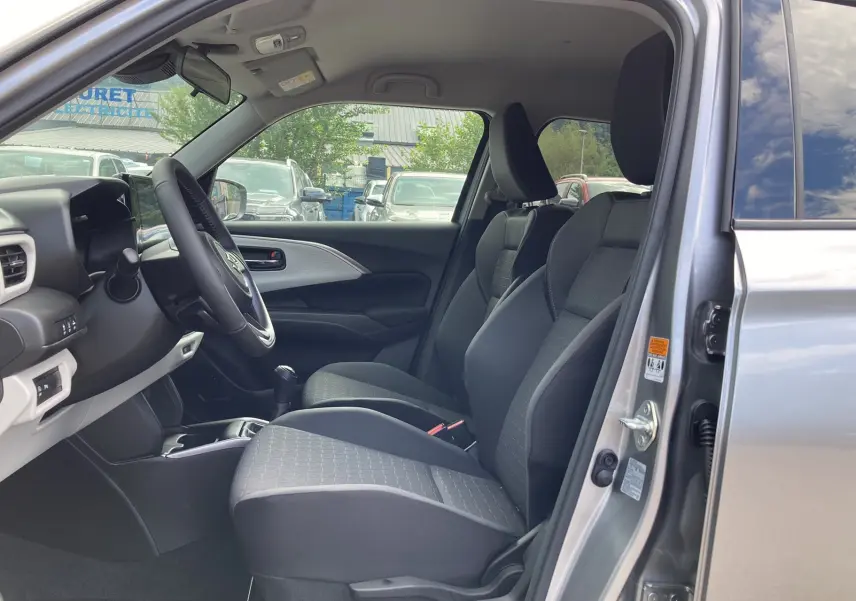 Intérieur côté conducteur d'une Suzuki Swift 2025 Premium silver metal, sièges tissu et volant cuir multifonctions visibles.
