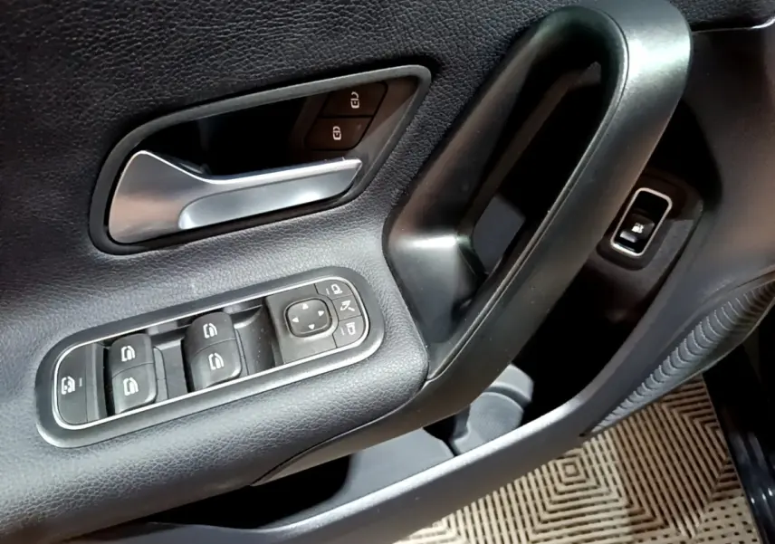 Gros plan sur la porte avant gauche noire de la Mercedes Classe A 250 e avec commandes de vitres et poignée intérieure.