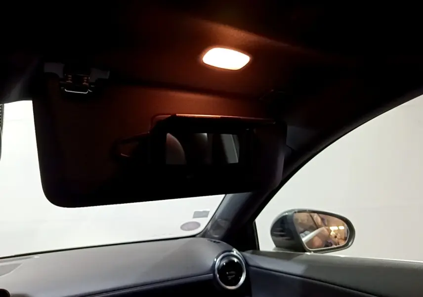 Vue intérieure côté passager avant du Mercedes Classe A 250 e Business Line 2020, avec pare-soleil abaissé et miroir éclairé.