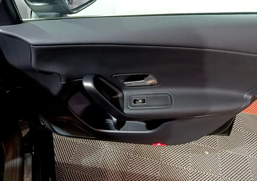 Vue intérieure côté gauche de la porte avant noire d'une Mercedes Classe A 250 e Business Line avec poignée et commande de vitre.
