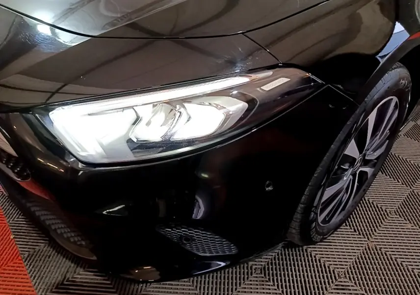 Gros plan sur l'avant droit noir d'une Mercedes Classe A 250 e avec phare LED et jante alliage visible.