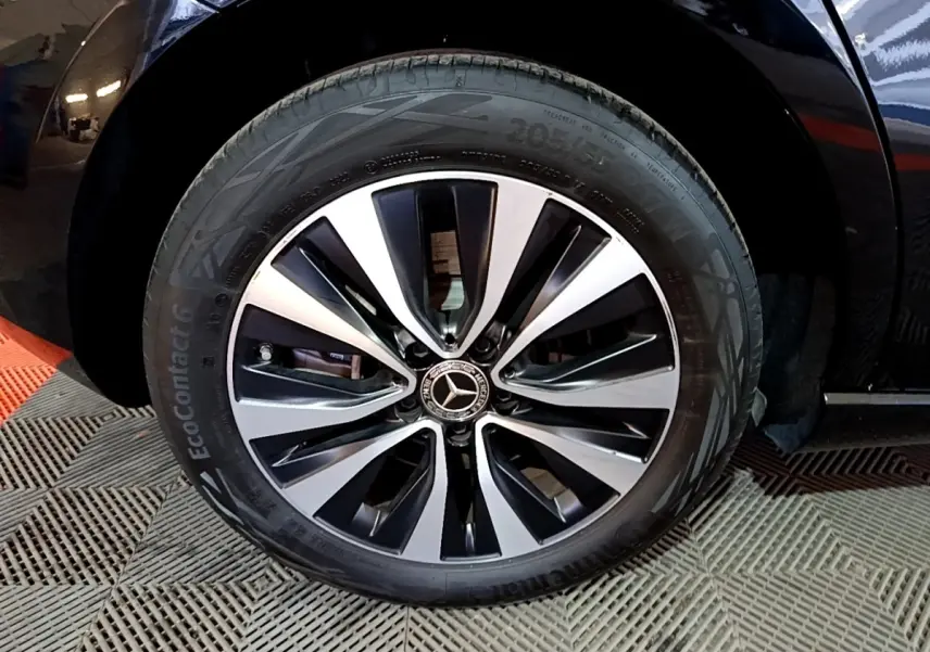 Gros plan sur la roue avant droite d'une Mercedes Classe A 250 e Business Line noire avec jante alliage bicolore.