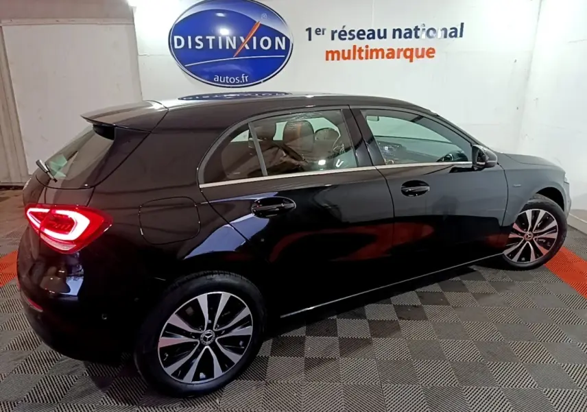 Vue 3/4 arrière côté gauche d'une Mercedes Classe A 250 e Business Line noire avec feux arrière LED allumés.