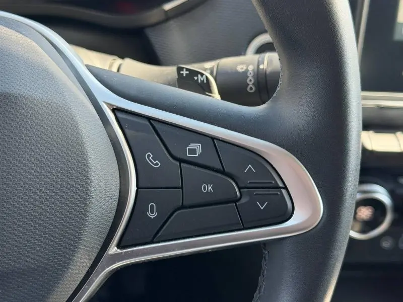 Gros plan sur les commandes multifonctions au volant côté gauche du Renault Arkana gris métallisé 2025.