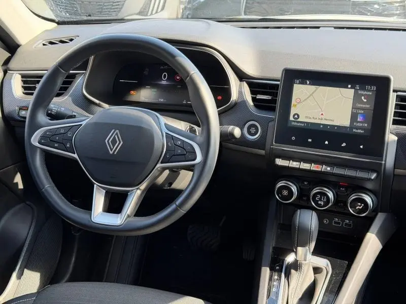 Vue intérieure du tableau de bord du Renault Arkana 2025 gris métallique, avec volant multifonction et écran tactile central.
