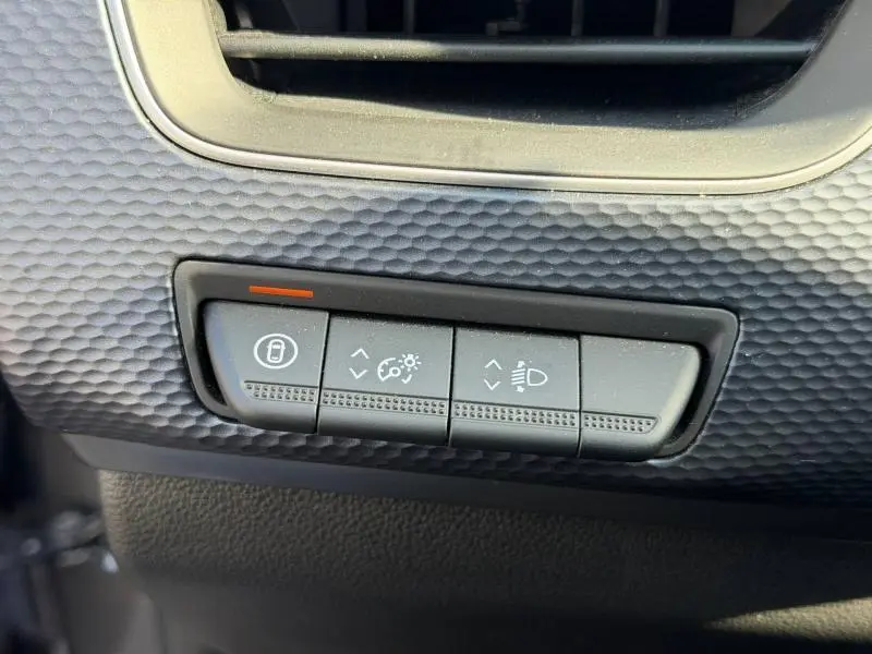 Détail intérieur montrant les commandes de réglage des phares et du tableau de bord sur Renault Arkana gris métallisé 2025.