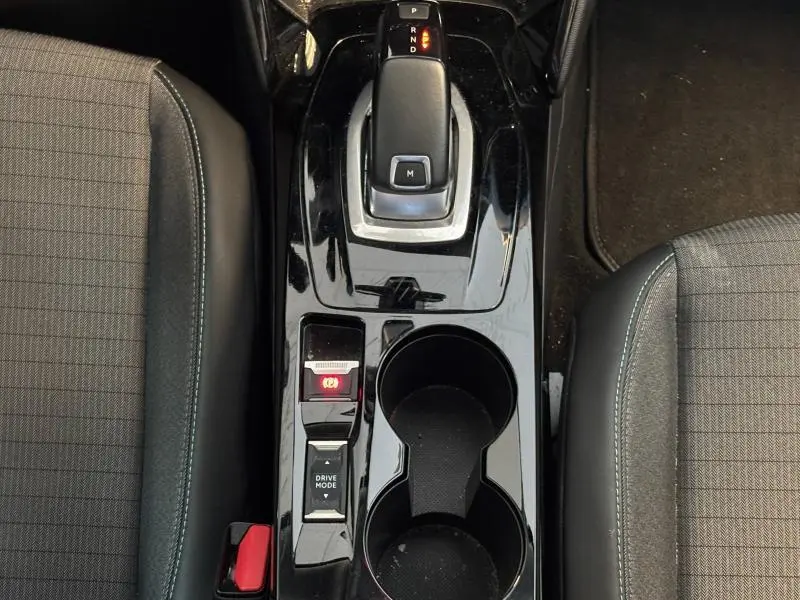 Vue plongeante sur la console centrale noire brillante du Peugeot 2008 2021 avec levier de vitesse automatique et porte-gobelets.