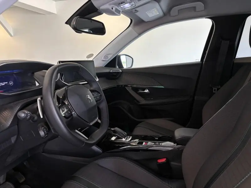 Vue intérieure côté conducteur du Peugeot 2008 2021 noir Perla Nera, avec volant compact et tableau de bord numérique 3D.