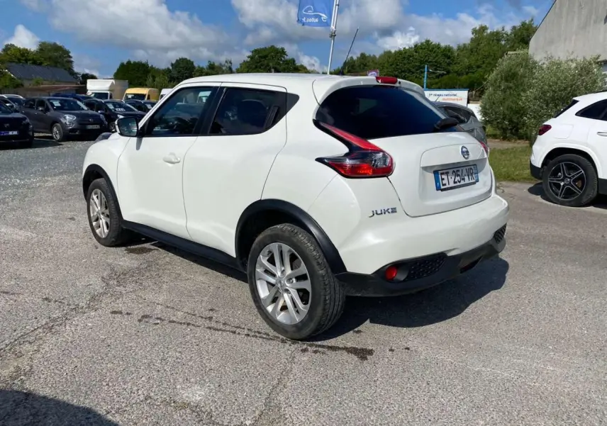 Nissan Juke blanc vue 3/4 arrière droit, vitres arrière surteintées et jantes alliage 17 pouces sport.