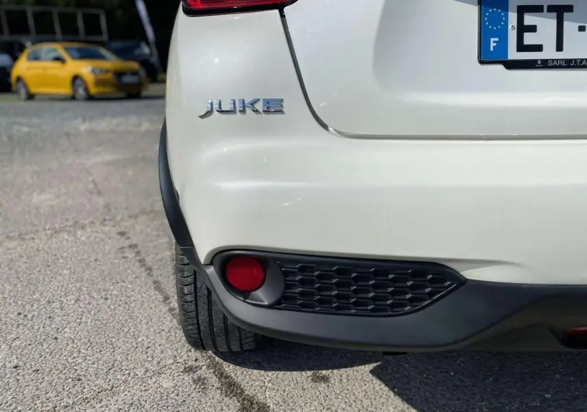 Gros plan sur l'arrière gauche blanc d'un Nissan Juke 2017 avec feu antibrouillard et logo visible.