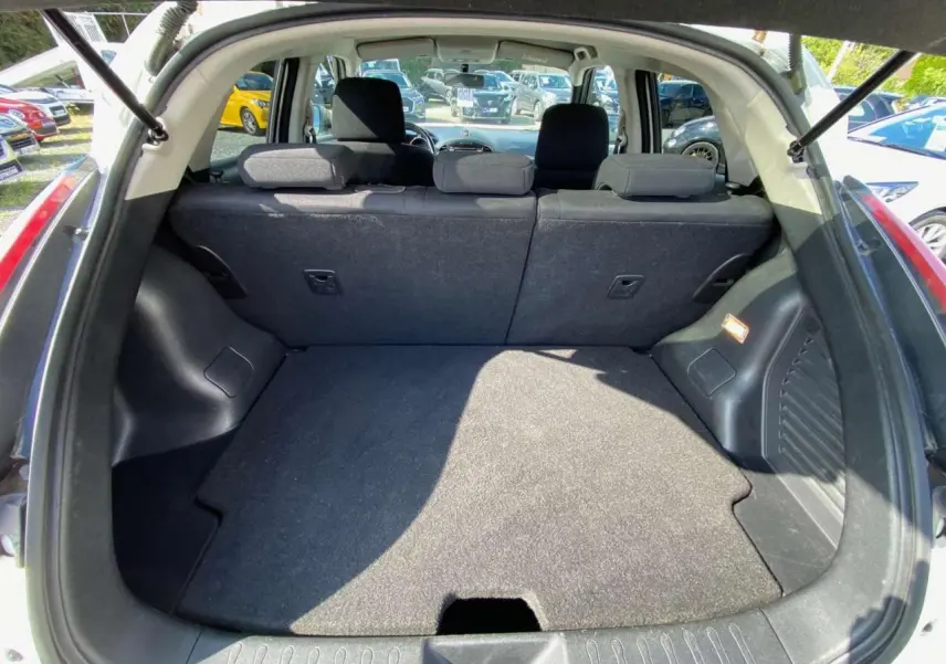 Coffre ouvert vu de l'arrière d'un Nissan Juke blanc 2017, montrant la banquette arrière et l'espace de chargement.