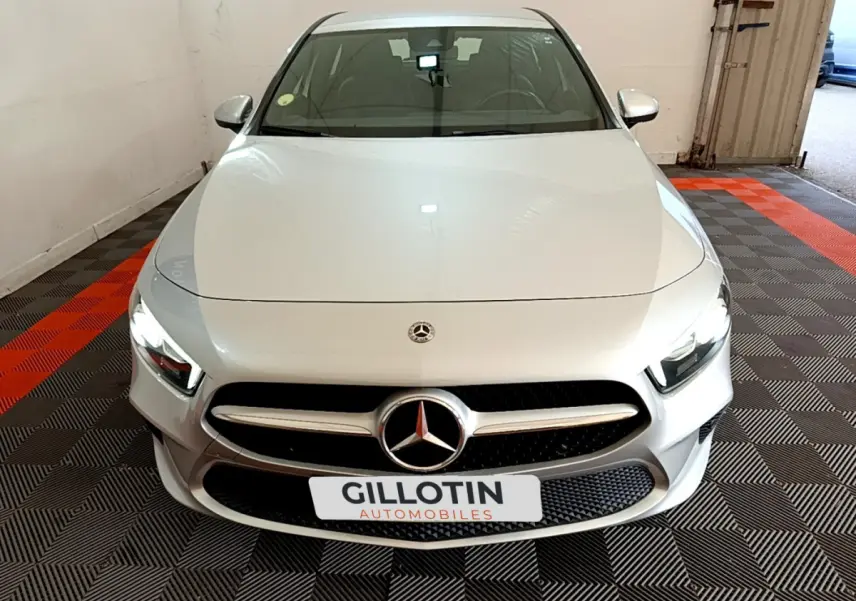 Vue avant d'une Mercedes Classe A gris clair avec calandre étoile et phares LED dans un garage.