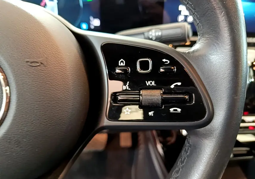 Gros plan sur les commandes de volume et fonctions vocales au volant cuir noir de la Mercedes Classe A 180 d Business Line 2020.