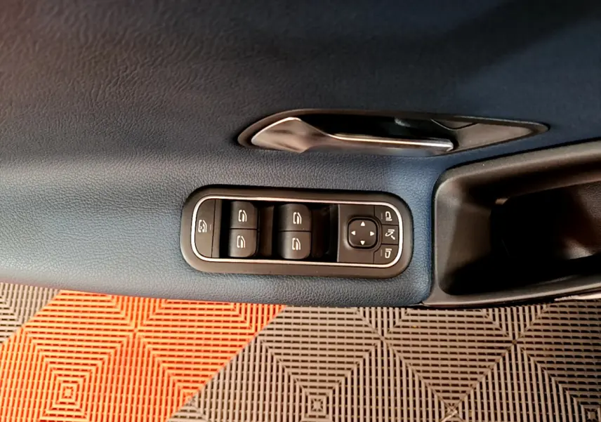 Gros plan sur la commande des vitres et rétroviseurs côté conducteur d'une Mercedes Classe A 180 d Business Line 2020, intérieur bleu.