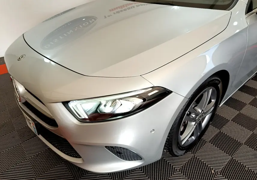 Vue 3/4 avant droit d'une Mercedes Classe A 180 d Business Line gris clair avec phares LED allumés.