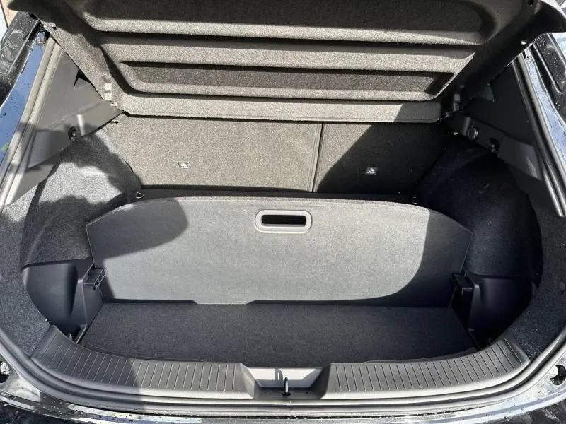 Coffre ouvert vu de dessus du Nissan Qashqai Hybrid e-POWER 2025 noir Kuro métallisé, montrant l'espace de rangement et la couverture de coffre.