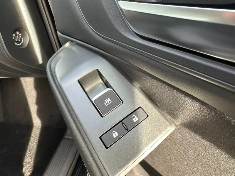 Gros plan sur les commandes de lève-vitre et verrouillage côté conducteur du Nissan Qashqai Hybrid e-POWER 2025 noir Kuro.